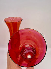 Red glass vase held by a hand against a white background