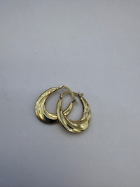 Pair of gold hoop earrings on a light gray background