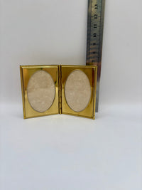 Gold compact frame with two oval lenses on a white background, next to a ruler for scale.