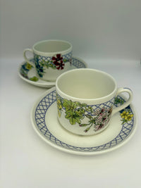 Two ceramic cups with floral patterns on saucers against a white background