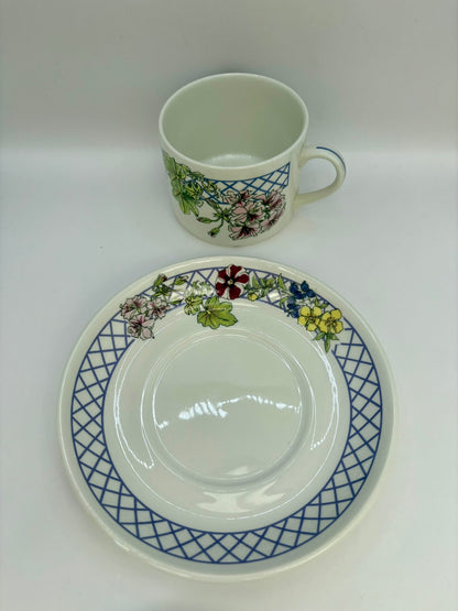 Ceramic cup and saucer with floral and geometric design on a white background