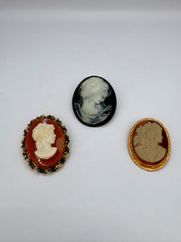 Three vintage-style cameo brooches on a white background