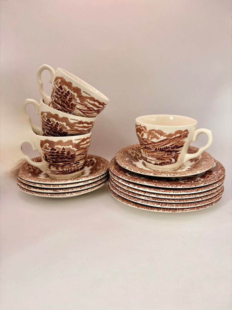 Set of ceramic teacups and saucers with brown floral patterns on a light gray background