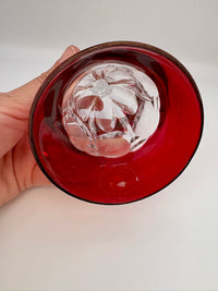 Hand holding a red glass bell with a clear crystal inside on a white background
