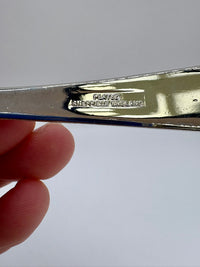 Silver object with 'Sheffield England' engraving held by a hand against a light background