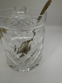 Clear glass jar with a silver spoon inside on a white background