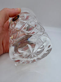 Hand holding a clear crystal heart-shaped object against a white background