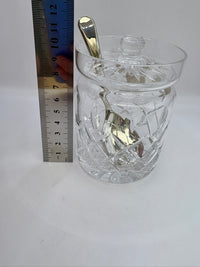 Clear glass with a spoon inside, next to a ruler for scale on a white background
