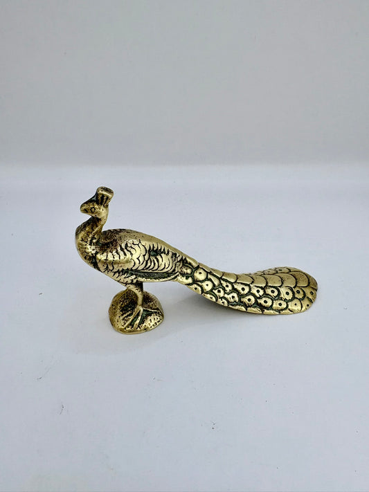 Brass peacock-shaped object on a white background