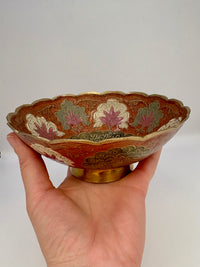 Decorative bowl held in a hand against a plain background