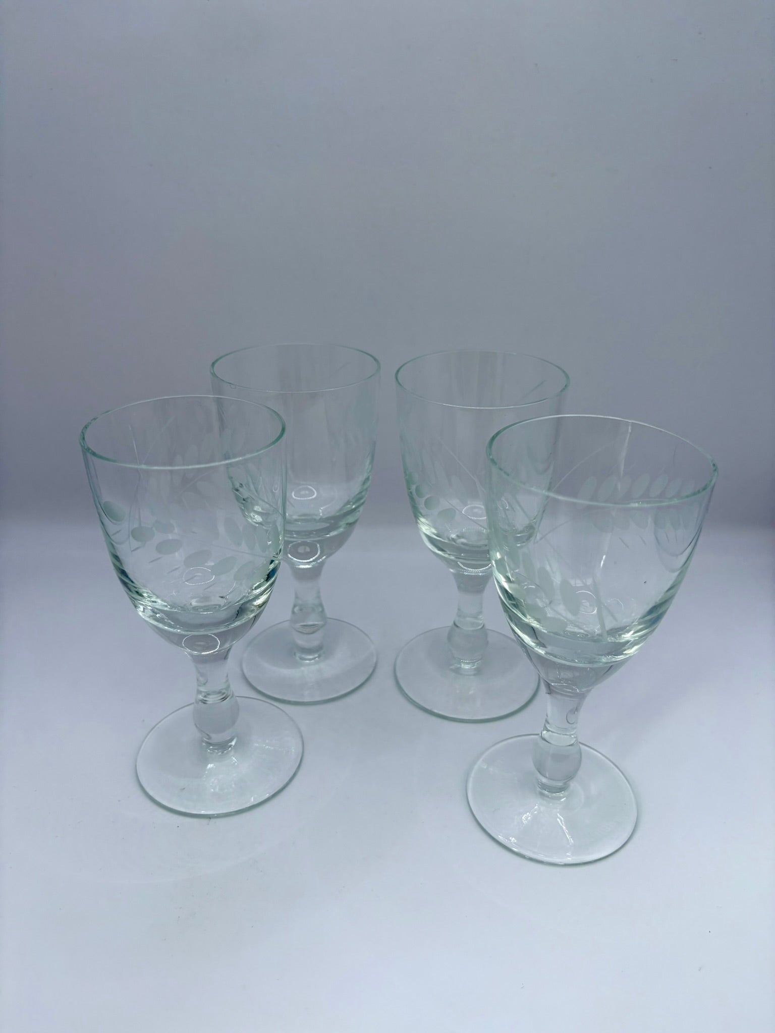 Set of four clear glass goblets on a white background