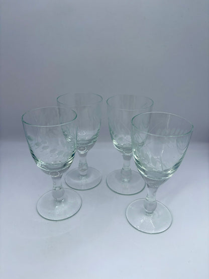 Set of four clear glass goblets on a white background