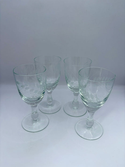 Set of four clear glass goblets on a white background