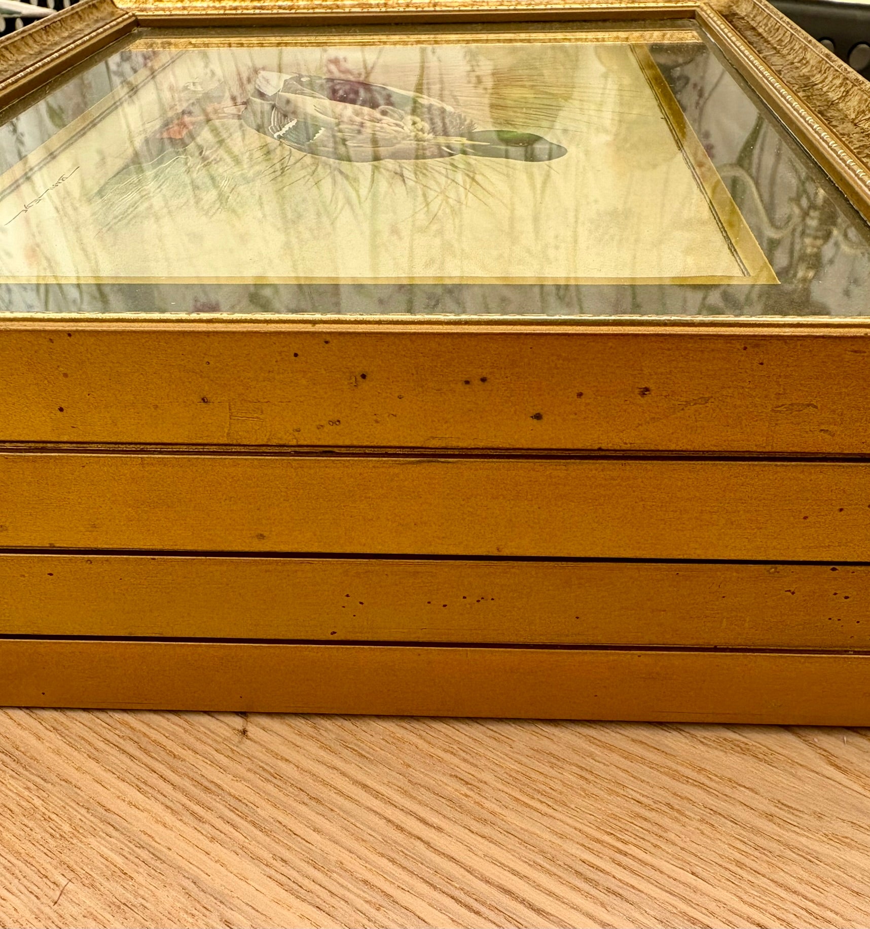 Gold-framed picture on a wooden surface