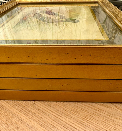 Gold-framed picture on a wooden surface