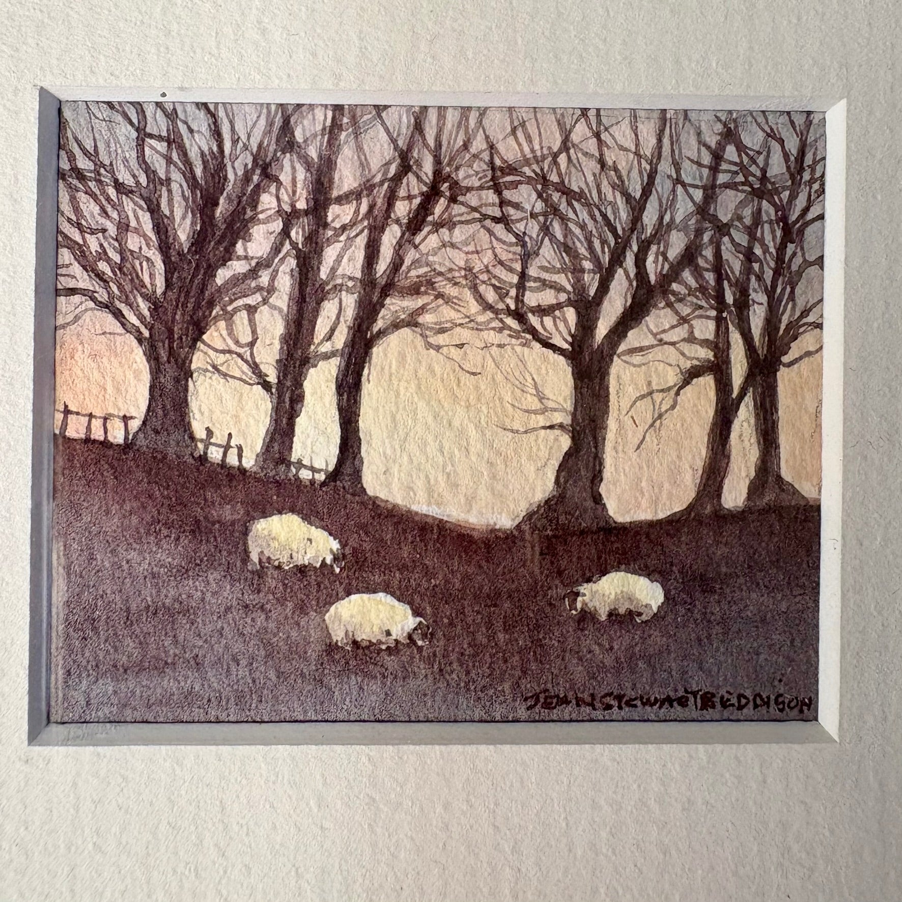 Framed artwork of sheep in a field with trees and a sunset.