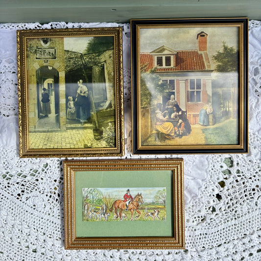 Three framed paintings on a textured white surface