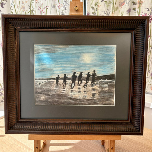 Framed artwork of people on a beach with a brown frame.