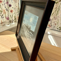 Framed photograph of a group of people on a beach with floral curtains in the background