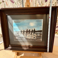 Framed artwork of silhouettes on a beach with a ruler for scale.