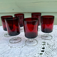 Set of red-tinted glass tumblers on a white lace tablecloth