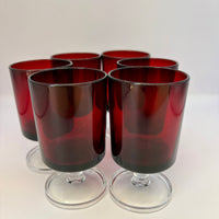 Set of six red-tinted glass tumblers on a white background