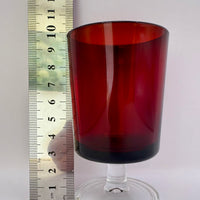 Red glass goblet next to a ruler on a white background