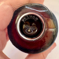 Close-up of a wine bottle cap with 'France' engraved on it, held in a hand.