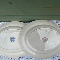 Two ceramic plates with visible branding on a textured surface.