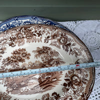 Decorative plate with floral and nature-themed design, partially covered by a measuring tape.