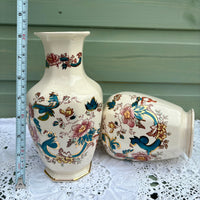 Two decorative vases with floral patterns on a white lace tablecloth, accompanied by a ruler for scale.