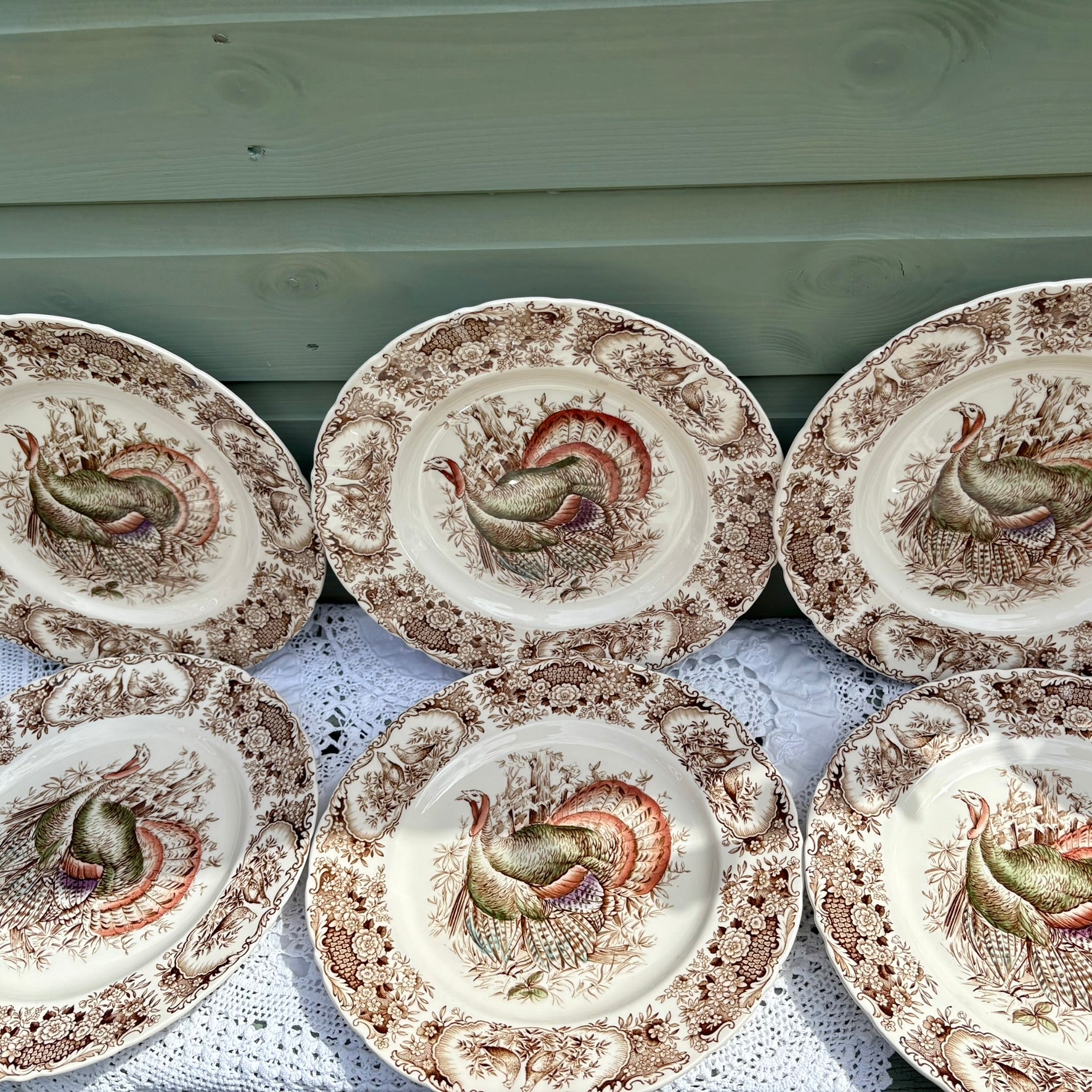 Set of ceramic plates with rooster designs on a wooden surface.