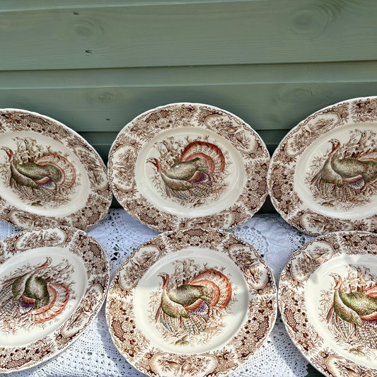 Set of ceramic plates with rooster designs on a wooden surface.