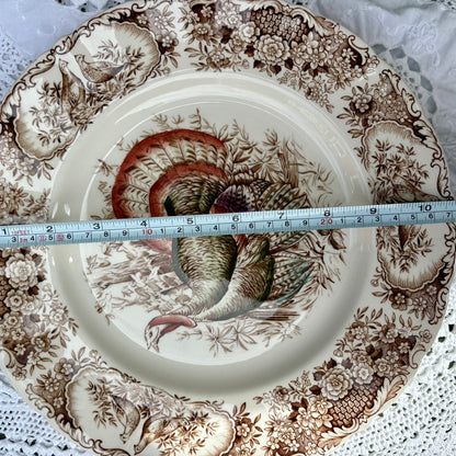 Decorative plate with a turkey design and floral patterns, measured against a ruler.