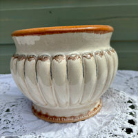 White ceramic pot with brown rim on a white lace tablecloth against a green wooden background