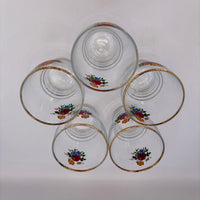 Set of five clear glasses with floral designs and gold rims on a white background