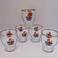 Set of five glass tumblers with floral designs on a white background
