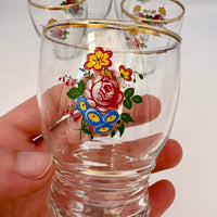 Clear glass with floral design held by a hand against a white background