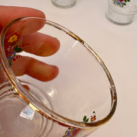 Clear glass with floral designs held by a hand on a light background