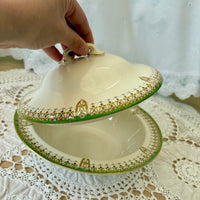 Decorative ceramic dish with gold and green patterns on a lace tablecloth