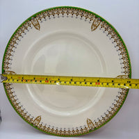 Measuring tape on a decorative plate with a green and gold border