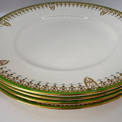 Set of four ornate plates with gold and green decorative rims on a white background