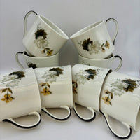Set of white ceramic mugs with floral patterns on a light gray background