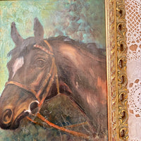 Painting of a horse's head with a decorative gold frame.