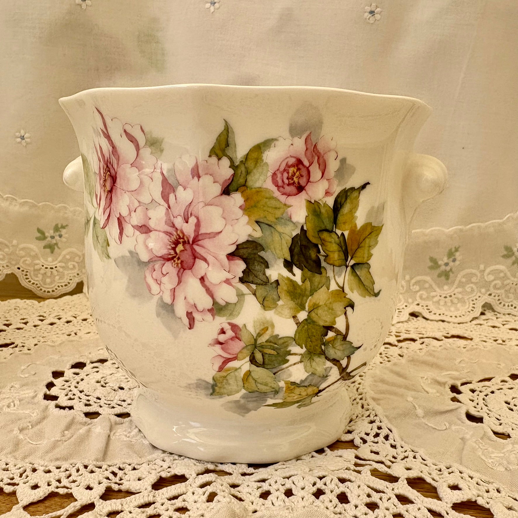 Decorative ceramic vase with floral design on a lace tablecloth
