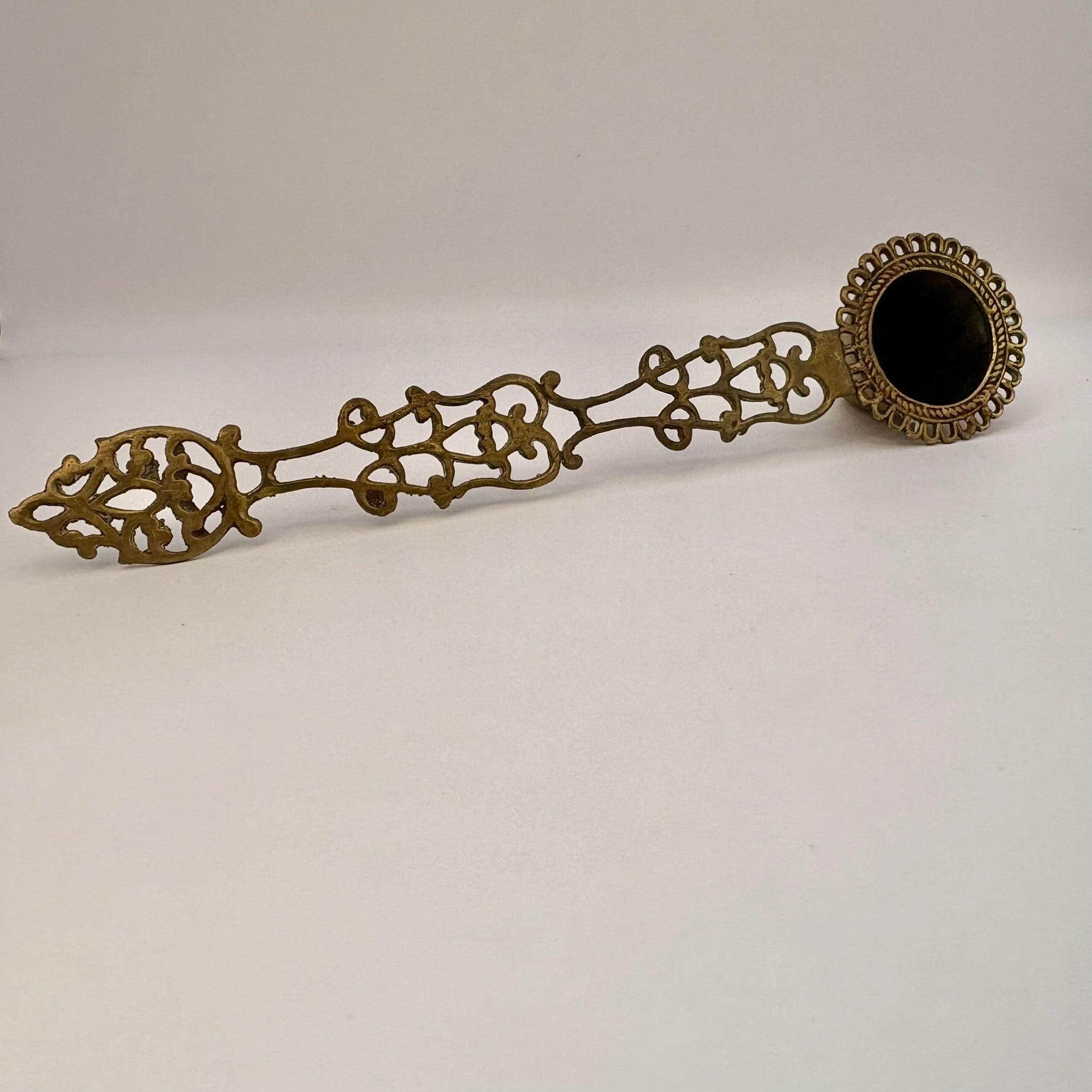 Decorative bronze spoon with intricate designs on a white background
