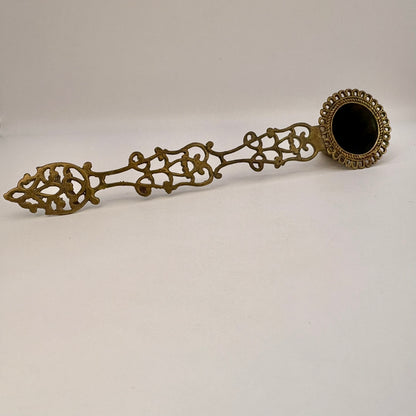 Decorative bronze spoon with intricate designs on a white background