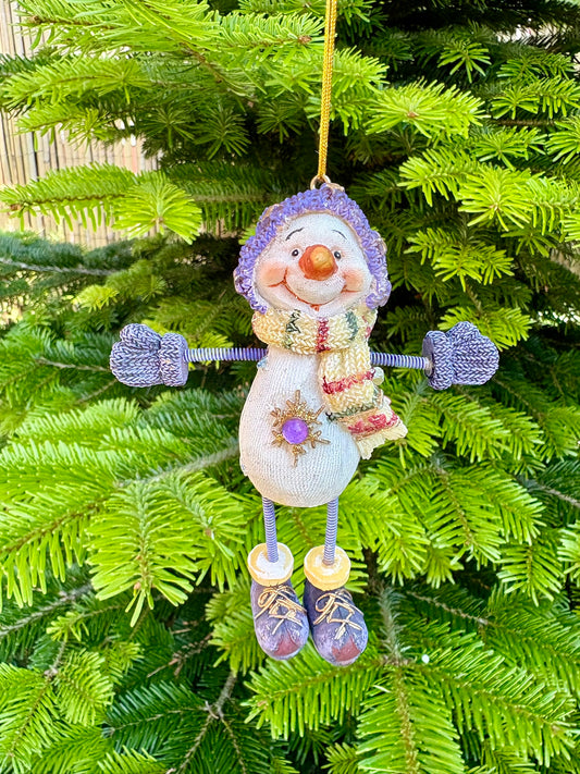 Decorative snowman ornament hanging on a Christmas tree
