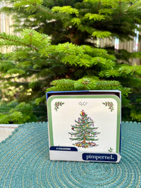 Set of coasters with a Christmas tree design on a green surface in front of a Christmas tree.