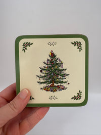 Hand holding a card with a Christmas tree design on a plain background